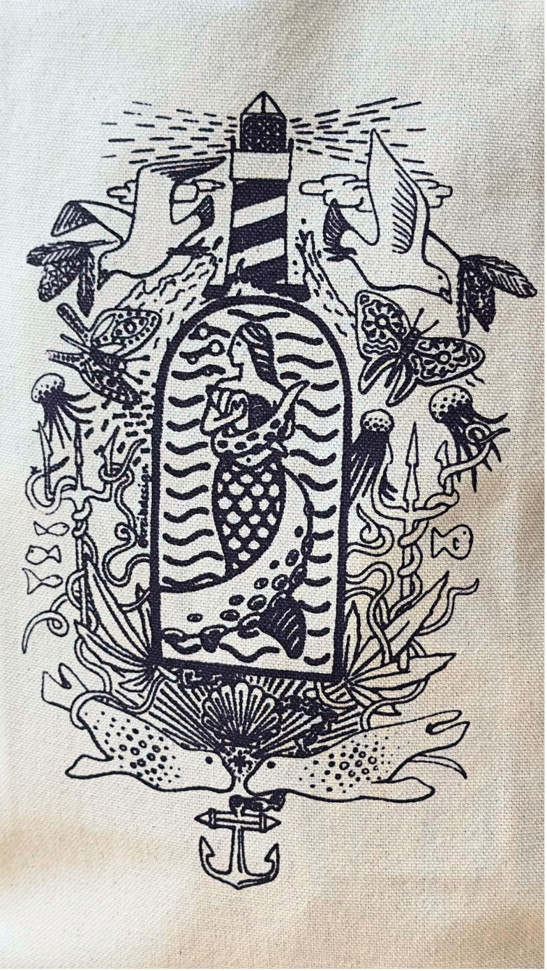 SeaWeed Co.s Canvas Tote - Purple features a black and white illustration of a mermaid inside a bottle, with fish, seashells, and seaweed. Birds and a lighthouse above, an anchor below evoke Maine adventures—perfect for this stylish bag.